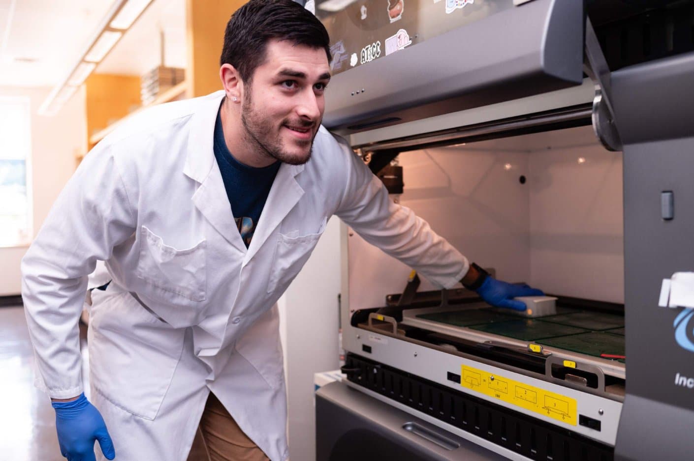 Scientist placing samples into a shaking incubator.