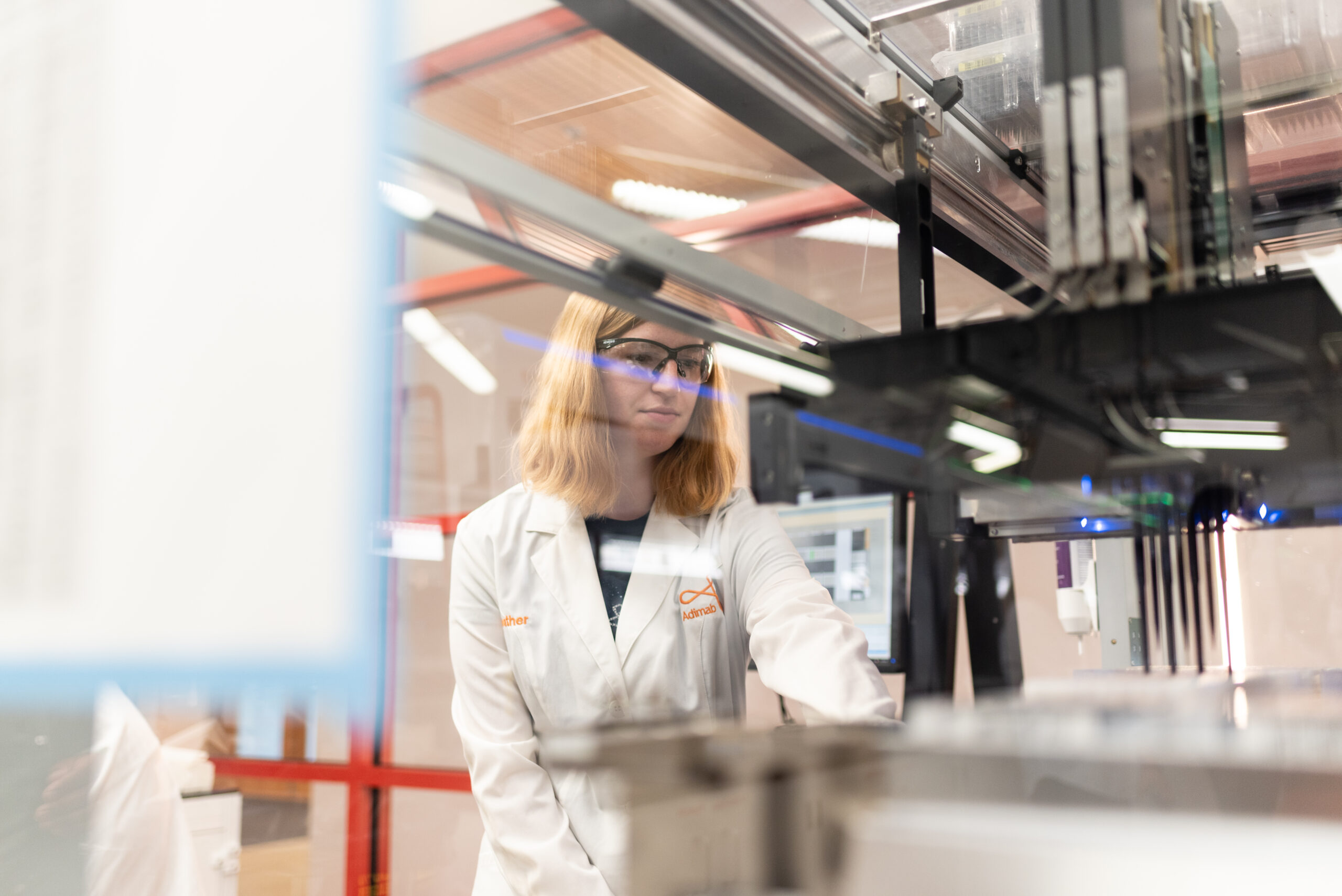 Scientist operating an automated liquid handling system in a laboratory.