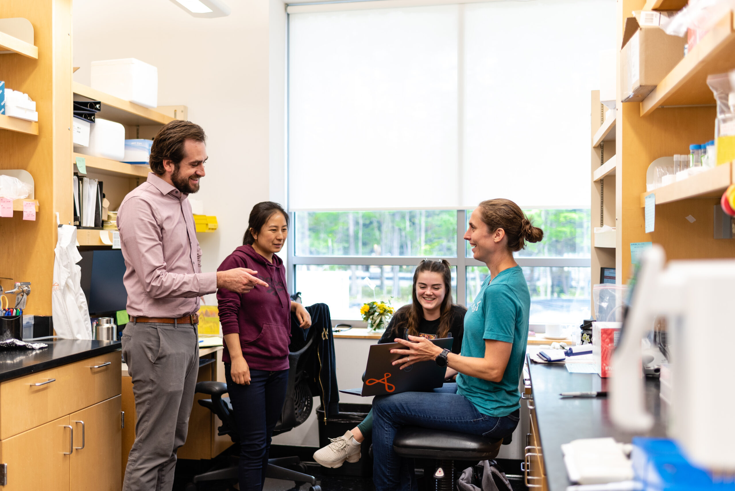 Group of scientists having a discussion in a research lab setting.