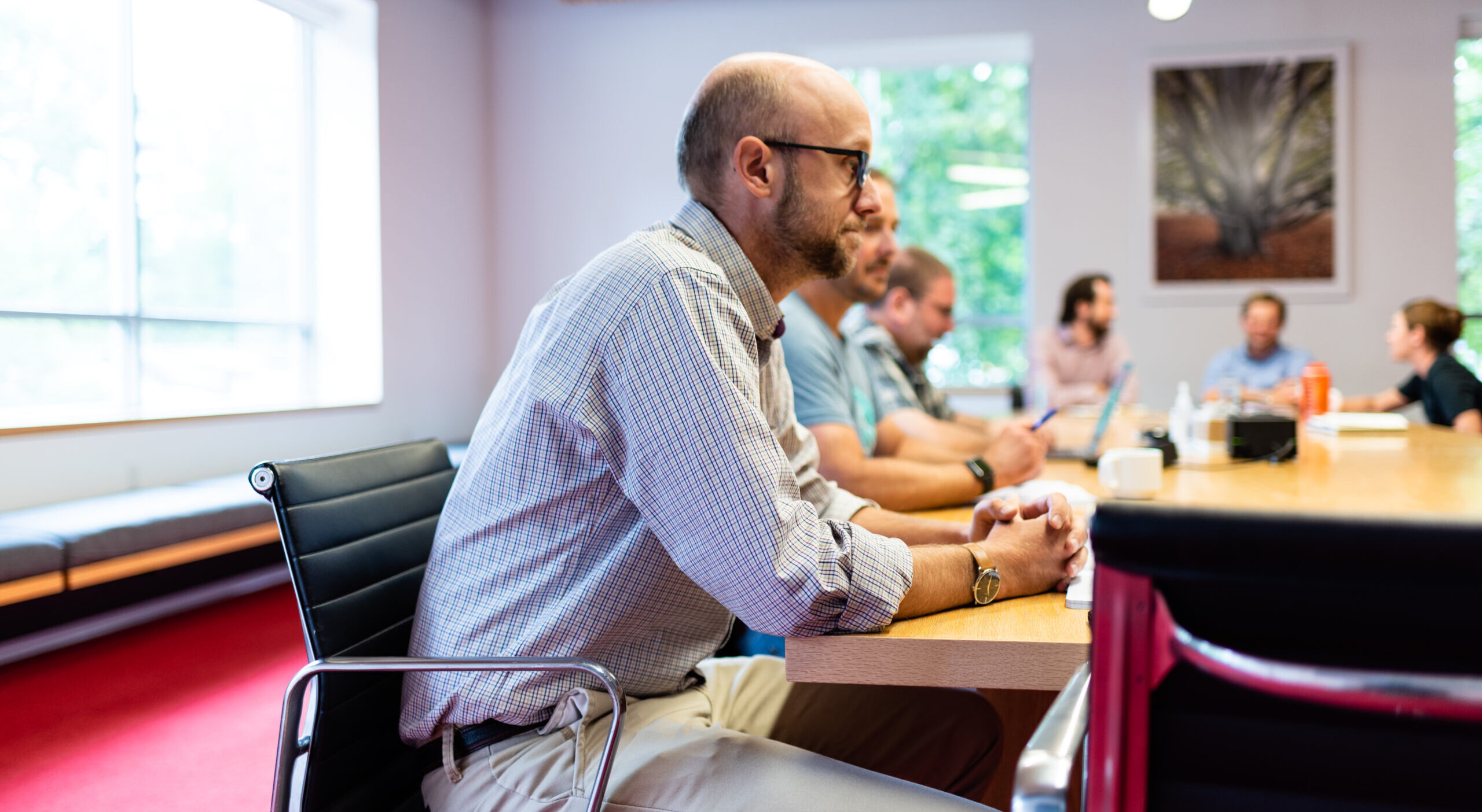 Leadership team members seated around a conference table during a meeting in a modern office space